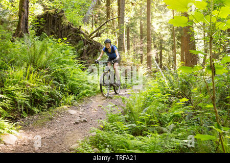 Happy, smiling woman having fun riding mountain bike biking on a trail. Women's outdoor adventure sports. Stock Photo