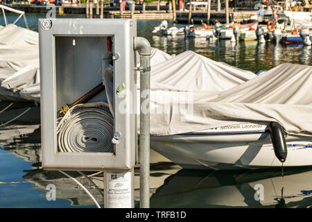 GARDA, LAKE GARDA, ITALY - SEPTEMBER 2018: Emergency fire hose in a metal box on the side of the harbour in Garda on Lake Garda. Stock Photo