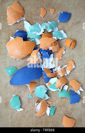 Colorful broken Easter eggshells on a wooden cutting board Stock Photo