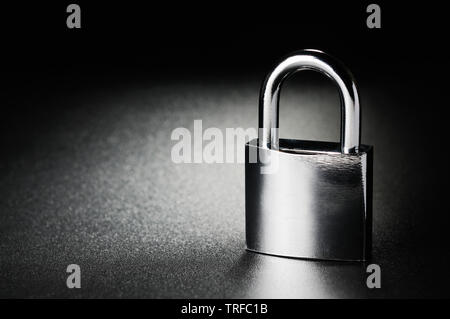 Steel padlock on the black textured background Stock Photo
