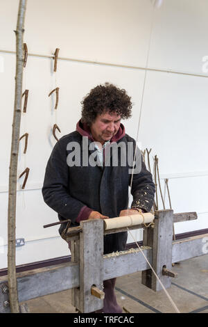 A man using a lathe wood turning carving and using chisels 