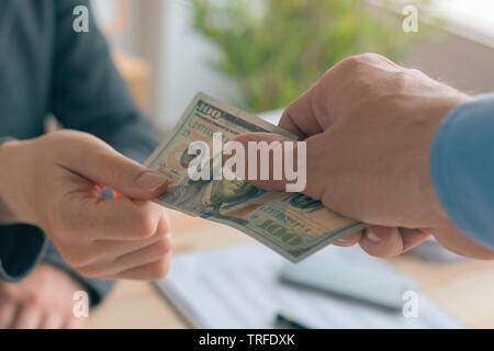 Hush money and corruption in business concept, close up of male hand giving hundred US dollar bill to female business person Stock Photo