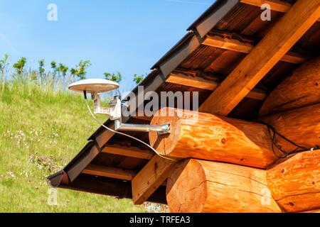 Satellite TV antenna on a wooden house. TV signal transmission. Internet Access. Telecommunication means. Stock Photo