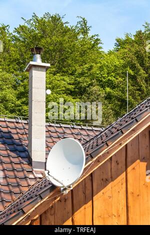 Satellite TV antenna on a wooden house. TV signal transmission. Internet Access. Telecommunication means. Stock Photo