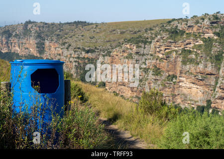 Bright blue rubbish bin with grass growing around it situated on the mountain hike in Oribi Gorge South Africa Stock Photo