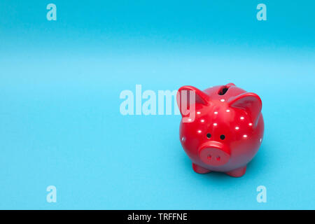 The classic red piggy bank in white polka dot on a blue background. Stock Photo