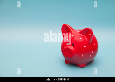 The classic red piggy bank in white polka dot on a blue background. Stock Photo