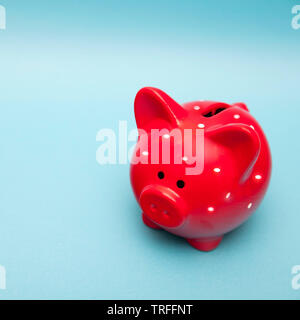 The classic red piggy bank in white polka dot on a blue background. Stock Photo