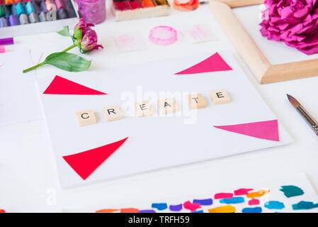 Side view close up creative artist workplace. Blank canvas with Create word lettering, variety of painting supplies and peony flowers. Drawing, inspir Stock Photo