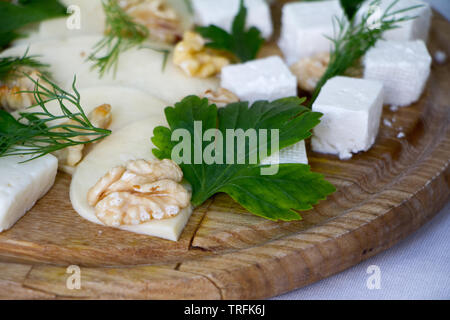 Extreme close-up of different types of cheeses, nuts, herbs and honey on a wooden board, the concept of a healthy snack, copyspace Stock Photo