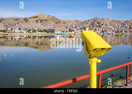 Binoculars at the malecón or pier in Puno Port on the Lake Titicaca with the city of Puno in the background, Puno, Peru Stock Photo