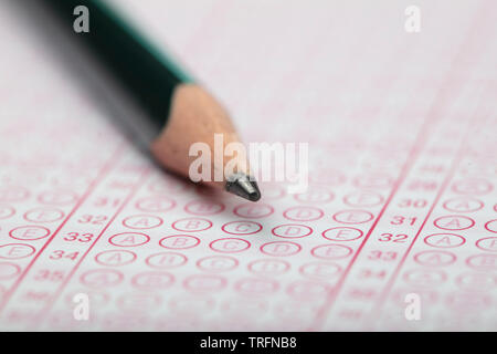 School Students hands taking exams, writing examination holding pencil on optical form of standardized test with answers sheet doing final exam in cla Stock Photo