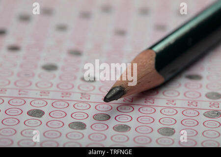 School Students hands taking exams, writing examination holding pencil on optical form of standardized test with answers sheet doing final exam in cla Stock Photo