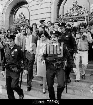 acting Mayor Dianne Feinstein and her husband Richard Blum leave San Francisco City Hall under police escort after Mayor Moscone and Harvey Milk were assassinated. San Francisco, 11/27/1978 Stock Photo