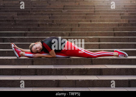 young woman doing the splits on stairs. Stock Photo