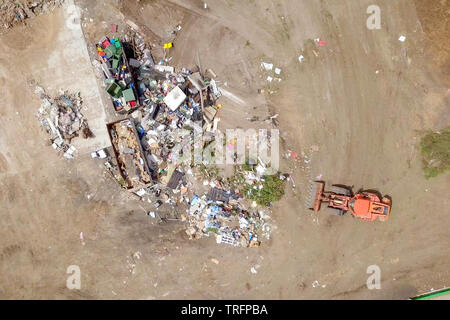 Orange Tractor working in a Waste sorting and recycling facility, Aerial footage. Stock Photo