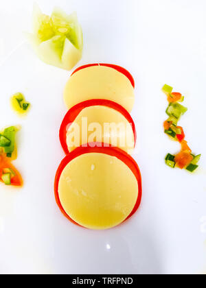 tomato and cheese wheels on a white plate Stock Photo