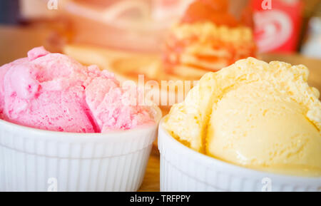 ice cream cup on wooden tray / Yellow vanilla and strawberry ice cream scoop on the table background top view Stock Photo