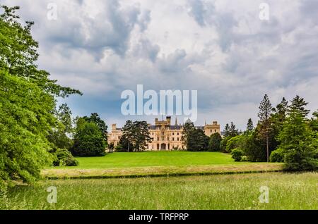 Lednice, Czech Republic - May 27 2019: View of Lednice castle in South Moravia with yellow facade over meadow. Garden with green lawn and trees. Stock Photo