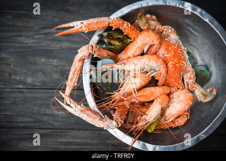 Shellfish seafood plate with steaming shrimps prawns mussel boiled in hot pot with herbs and spices on dark background Stock Photo