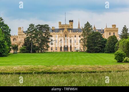 Lednice, Czech Republic - May 27 2019: View of Lednice castle in South Moravia with yellow facade over green meadow and trees. Sunny spring day. Stock Photo