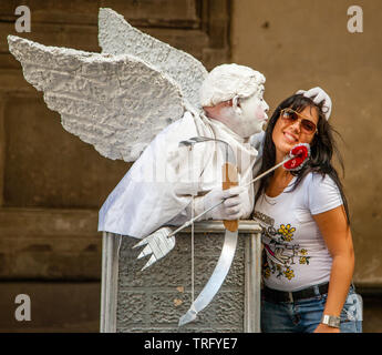 Cupid street performer working his spell on a smiling woman in Florence Italy Stock Photo