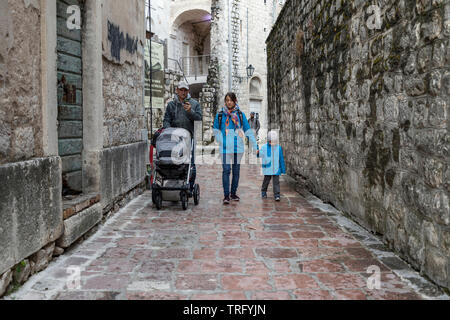 Montenegro, April 30, 2019: A family walking down the narrow cobblestone street in Kotor Old Town Stock Photo