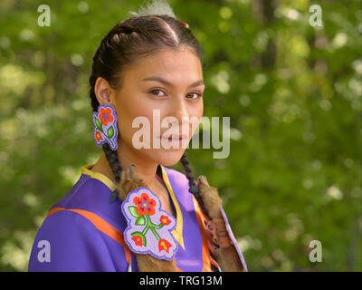 Young Canadian Cree First Nations woman wears her traditional regalia and poses for the camera during the Barrie Native Friendship Centre Pow Wow. Stock Photo