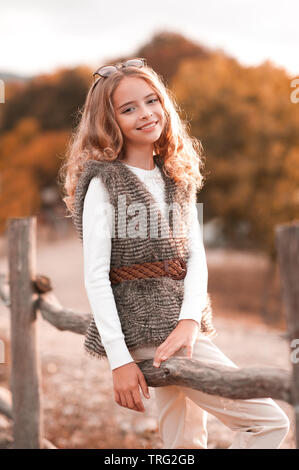 Beautiful blonde teen girl 13-14 year old wearing stylish clothes posing in  autumn park. Looking at camera Stock Photo - Alamy