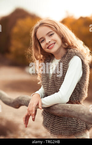 Beautiful teen girl 14-15 year old wearing stylish clothes sitting  outdoors. Looking at camera. Autumn season. Stock Photo