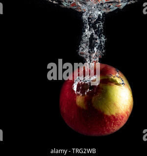 red ripe Apple falls into the water with splashes Stock Photo