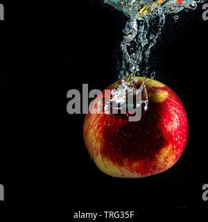 red ripe Apple falls into the water with splashes Stock Photo