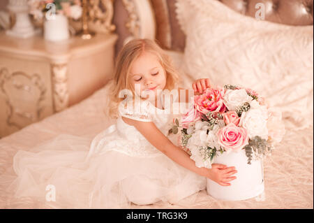 Smiling baby girl 3-4 year old holding flowers wearing white stylish dress  sitting in bed. Happy birthday Stock Photo - Alamy