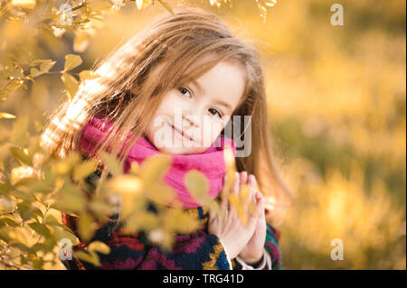 Smiling kid girl 4-5 year old posing outdoors in autumn. Looking at camera. Stock Photo