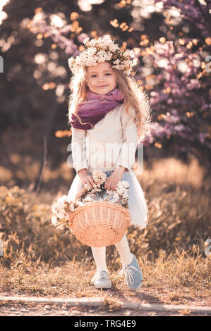 Happy kid girl 5-6 year old wearing casual clothes outdoors. Holding flower basket. Looking at camera. Childhood. Stock Photo