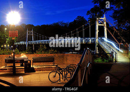 The suspension bridge over Teddington Lock allowing pedestrians to cross the river Thames from Ham to Teddington, Middlesex. Photographed at night. Stock Photo