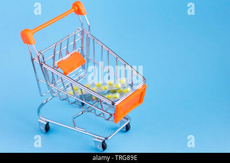 supermarket shopping cart with pills on blue background Stock Photo