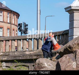 Volunteer at annual Spring clean on bank of Water of Leith, Edinburgh, Scotland, UK. A young boy retrieves a traffic cone from the riverbank Stock Photo