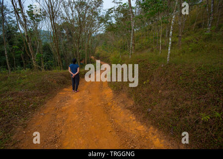 Woman walking along an earthen trail in Wayanad (Kerala, India) Stock Photo