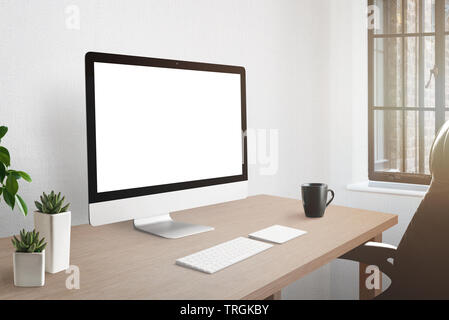 Workroom desk with computer display with isolated screen for mockup. Plants and cup of coffee beside. Stock Photo