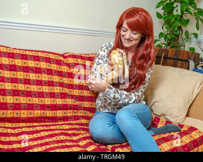 Young woman relaxing in the house with her exotic pet snakes and reptiles, she runs a reptile shelter for reptiles in need. Stock Photo