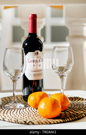 Torrevieja, Spain - April 11, 2019: Close up bottle Campo Viejo Rioja two empty clear wine glasses and three orange mandarin fruits on place mat Stock Photo