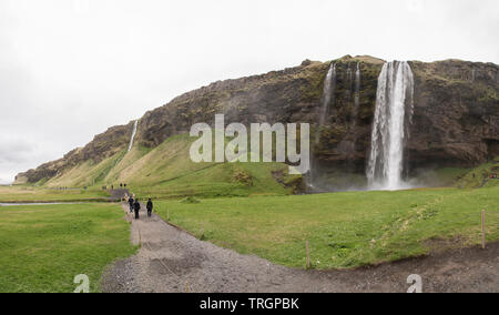 SELJALANDSFOSS, Iceland - May 30, 2018: Tourists walk on a path near Seljalandsfoss on an overcast day. Editorial use only. Stock Photo