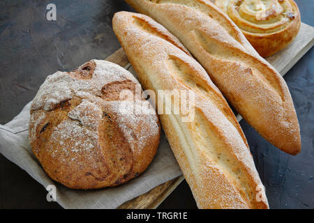 Freshly baked baguettes, bread and bun on a linen napkin. Stock Photo