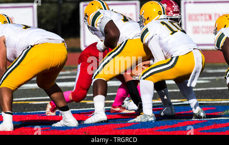 A high school quarter back is backing up after receiving the football from his center to start a play during a game. Stock Photo