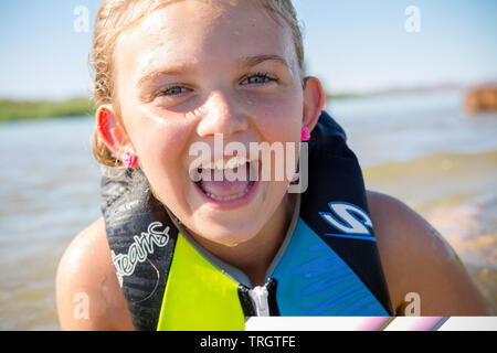 Girl playing in the water with life jacket during the summer, smiling laughing Stock Photo
