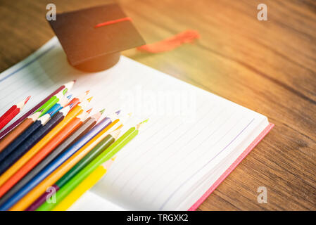 Colored pencil set and graduation cap on white paper notebook back to school and education concept / Crayons colorful Stock Photo