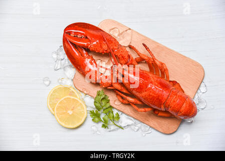 Lobster seafood with ice on wooden cutting board and lemon coriander / Close up of steamed lobster food Stock Photo