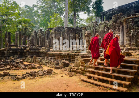 Three Buddhist monks enter the Bayon Temple at Ankor Wat, Siem Reap, Cambodia Stock Photo