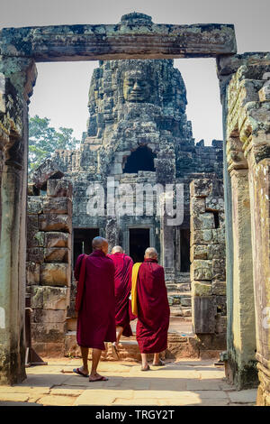 Three Buddhist monks enter the Bayon Temple at Ankor Wat, Siem Reap, Cambodia Stock Photo